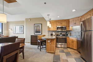 Kitchen with pendant lighting, stainless steel appliances, light stone countertops, and decorative backsplash