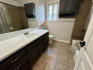 Full bathroom with shower / tub combo with curtain, tile patterned flooring, vanity, and toilet