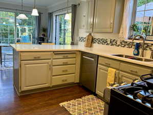 Kitchen with kitchen peninsula, sink, dark wood-type flooring, and decorative light fixtures