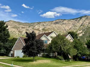 View of front facade featuring a mountain view, a front lawn, a porch, and a garage