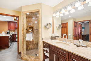 Bathroom with a tile shower, tile patterned flooring, and vanity