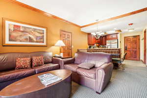 Living room featuring crown molding, light carpet, and a chandelier