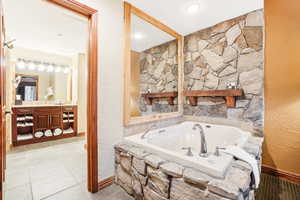 Bathroom featuring tiled bath, vanity, and tile patterned floors