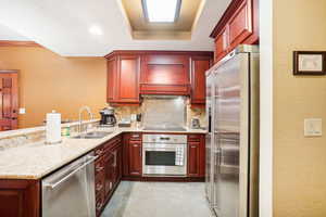 Kitchen with tasteful backsplash, sink, kitchen peninsula, appliances with stainless steel finishes, and premium range hood