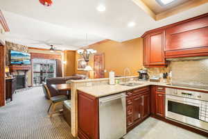 Kitchen featuring pendant lighting, sink, kitchen peninsula, appliances with stainless steel finishes, and a stone fireplace