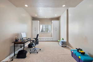 Carpeted office space with a textured ceiling