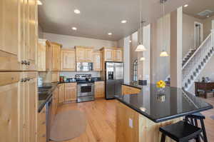 Kitchen featuring pendant lighting, a kitchen island, light hardwood / wood-style flooring, stainless steel appliances, and light brown cabinetry