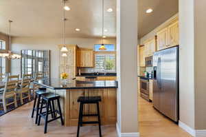 Kitchen with appliances with stainless steel finishes, a kitchen bar, pendant lighting, and light hardwood / wood-style flooring