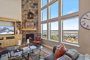 Carpeted living room featuring a stone fireplace, a towering ceiling, and a wealth of natural light