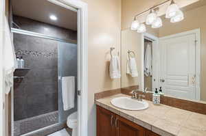 Bathroom featuring a tile shower, vanity, and toilet