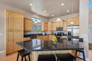 Kitchen featuring pendant lighting, a breakfast bar area, appliances with stainless steel finishes, and light hardwood / wood-style flooring