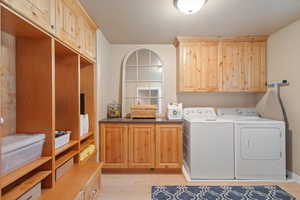 Laundry room featuring washer and clothes dryer, light hardwood / wood-style floors, and cabinets