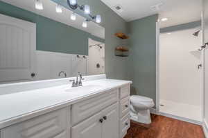 Bathroom with walk in shower, hardwood / wood-style flooring, vanity, and toilet