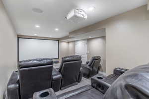 View of cinema room with 5 recliners and stadium seating, projector and large screen, built in sound system.