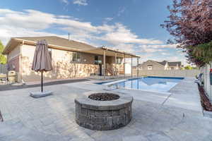 View of swimming pool with a natural gas fire pit, a diving board, and a patio area