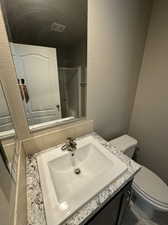 Bathroom featuring decorative backsplash, an enclosed shower, vanity, and toilet