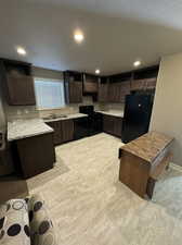 Kitchen with a textured ceiling, black appliances, dark brown cabinets, and a center island