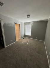 Carpeted spare room featuring a textured ceiling