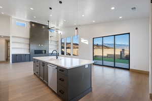 Kitchen featuring a mountain view, a center island with sink, sink, hanging light fixtures, and stainless steel dishwasher