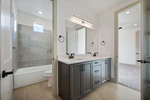 Full bathroom featuring tiled shower / bath, vanity, wood-type flooring, and toilet