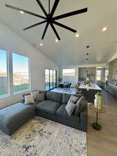 Living room with lofted ceiling, sink, ceiling fan, light wood-type flooring, and a textured ceiling