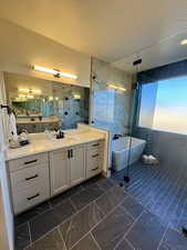 Bathroom with plus walk in shower, a textured ceiling, vanity, and tile walls