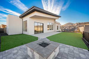 Rear view of property with a patio, an outdoor fire pit, and a lawn