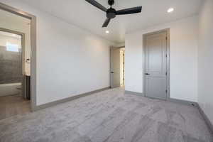 Unfurnished bedroom with ensuite bath, ceiling fan, a closet, and light colored carpet