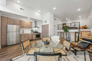 Dining space with a towering ceiling, light hardwood / wood-style flooring, and sink