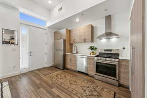 Kitchen featuring wall chimney exhaust hood, dark hardwood / wood-style floors, sink, and stainless steel appliances