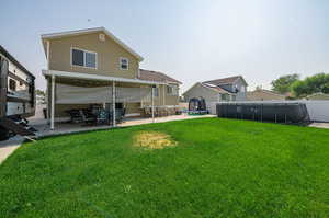 Rear view of house with a trampoline, a patio area, and a yard