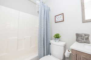 Full bathroom featuring vanity, toilet, and shower / bathtub combination with curtain