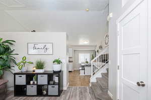 Foyer with vaulted ceiling, a textured ceiling, and hardwood / wood-style flooring