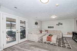 Living room featuring french doors, a textured ceiling, and hardwood / wood-style floors