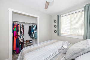 Bedroom featuring a textured ceiling, hardwood / wood-style flooring, ceiling fan, and a closet