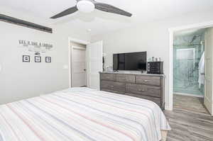 Bedroom featuring light hardwood / wood-style floors, a textured ceiling, a barn door, connected bathroom, and ceiling fan