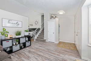 Entryway featuring lofted ceiling, light hardwood / wood-style floors, and a textured ceiling