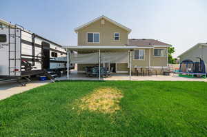 Back of property with a patio, a trampoline, and a yard