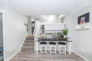 Kitchen featuring a breakfast bar, light wood-type flooring, lofted ceiling, and a textured ceiling