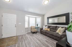 Living room with lofted ceiling and light hardwood / wood-style floors