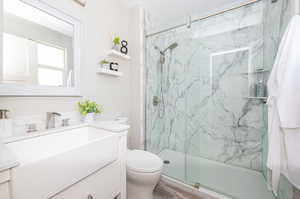 Bathroom featuring hardwood / wood-style floors, a shower with shower door, vanity, and toilet