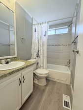 Bathroom featuring shower / bath combination with curtain, vanity, visible vents, toilet, and wood finished floors