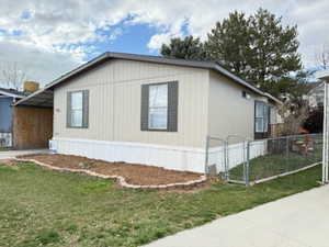View of side of home with a gate, fence, and a yard