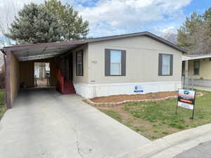 Manufactured / mobile home with an attached carport, a front yard, and concrete driveway