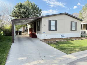 Manufactured / mobile home featuring a front lawn, an attached carport, and concrete driveway
