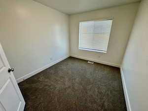 Empty room featuring dark colored carpet