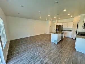 Kitchen with sink, a kitchen island with sink, white cabinetry, stainless steel appliances, and hardwood / wood-style floors