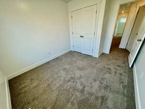 Unfurnished bedroom with light carpet and a closet