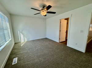 Unfurnished bedroom featuring ceiling fan and dark colored carpet