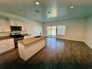 Kitchen with sink, a kitchen island with sink, white cabinetry, appliances with stainless steel finishes, and dark hardwood / wood-style floors